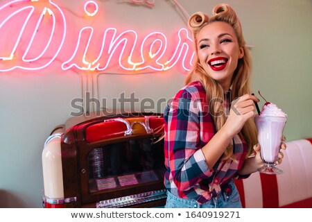 Stockfoto: Photo Of Young Cheerful Woman Drinking Milkshake While Leaning Jukebox