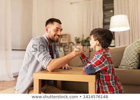 Stok fotoğraf: Happy Father And Little Son Arm Wrestling At Home