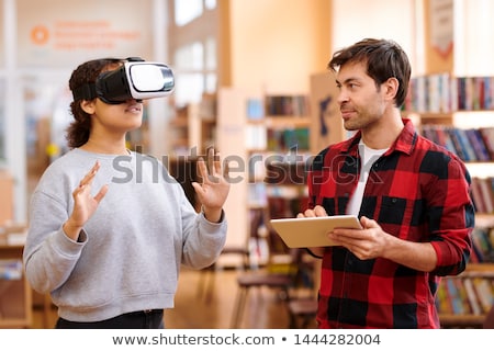 Stok fotoğraf: Young Man With Tablet Interacting With His Classmate In Vr Headset