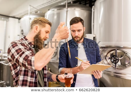 Foto stock: Men With Pipette Testing Craft Beer At Brewery