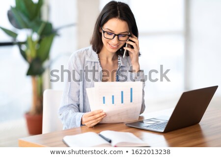 Stockfoto: Businesswoman Looking At Documents While Talking By Phone