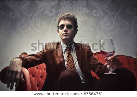 Stok fotoğraf: Portrait Of A Seated Elegant Man Holding Sunglasses