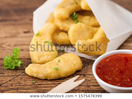 Foto d'archivio: Buttered Chicken Nuggets In Paper Bag With Wooden Forks And Ketchup On Wooden Background