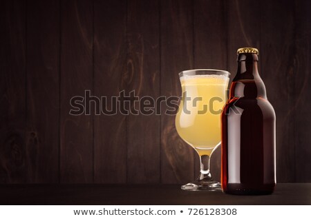 Foto d'archivio: Brown Beer Bottle Belgian Steinie And Glass Tulip With Muddy Weizen On Dark Wood Board Copy Space