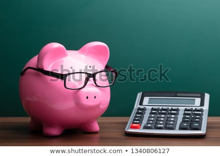 Stockfoto: Piggybank And Calculator In Front Of Green Board