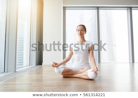 Foto stock: Young Woman Practicing Yoga Lotus Position In Apartment