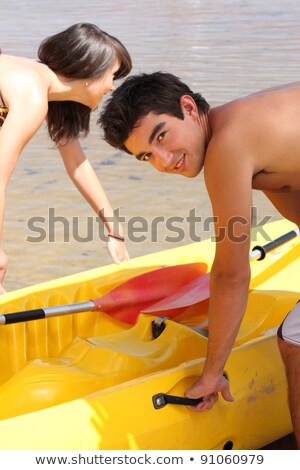 [[stock_photo]]: Young Couple Putting A Canoe In The Water