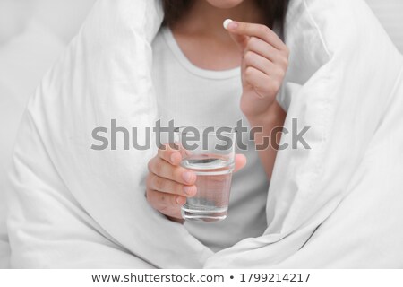 Foto stock: Woman In Bed Holding Pills And Glass Of Water