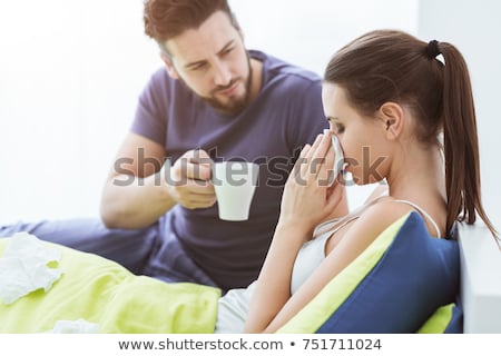 Stockfoto: Young Man Sneezing For Cold In Bed With Partner