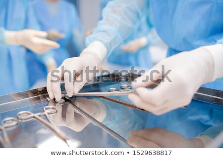 Stock fotó: Gloved Hands Of Surgeon Or Assistant Taking One Of Sterile Instruments