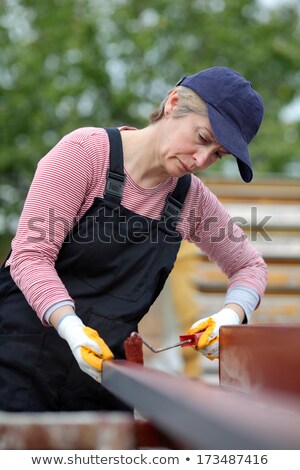 Foto stock: Serious Female Worker Painting Tube With Paintroller Real People Selective Focus And No Retouching