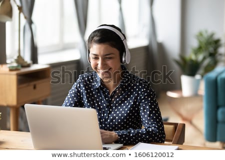 Сток-фото: Young Businesswoman In Headphones Working On A Laptop At Office