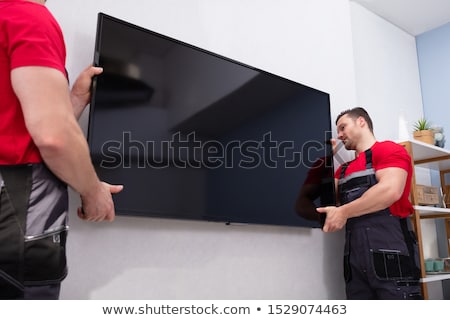 Stok fotoğraf: Male Movers Fixing The Large Lcd Television On Wall