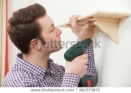 Stock fotó: Man Putting Up Wooden Shelf At Home Using Electric Cordless Dril