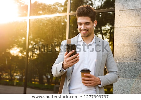 Stok fotoğraf: Photo Of Smiling Businessman In Suit Holding Mobile Phone While