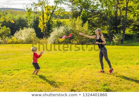 ストックフォト: Mother And Son Playing With A Large Model Toy Aeroplane In The Park