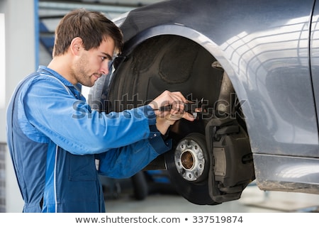 Stok fotoğraf: Car Mechanic Examining Brake Disc With Caliper