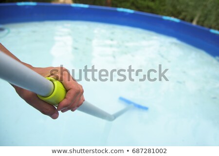 Stockfoto: Young Man Cleaning A Portable Swimming Pool