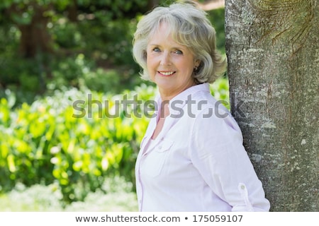 Zdjęcia stock: Portrait Of A Smiling Senior Woman Leaning On A Tree