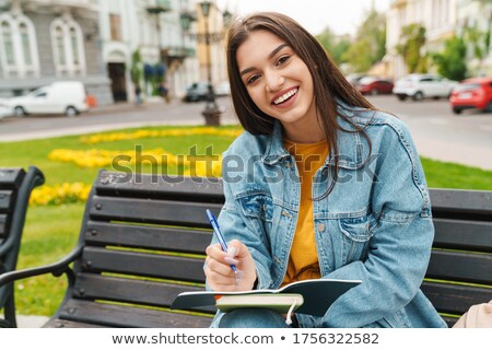 Stok fotoğraf: Photo Of Thinking Brunette Woman Smiling While Making Notes In Diary