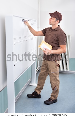 Foto stock: Postman Putting Letters In Mailbox