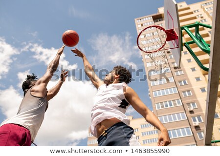 Stok fotoğraf: Below View Of Two Intercultural Rivals Trying To Catch Ball In Motion