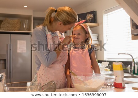 ストックフォト: Front View Of Happy Mother Doting On Her Daughter While Preparing Food In Kitchen At Home
