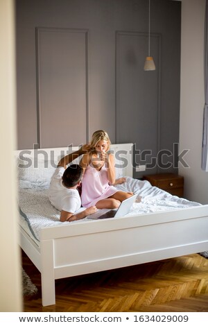 Stock foto: Intimate Lovers Using Laptop Sitting On The Bed In The Bedroom