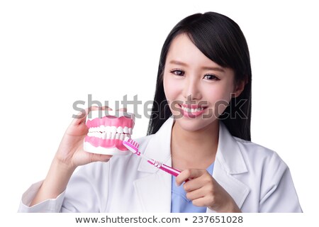 Stock photo: Young Dentist In Uniform Brushing False Teeth With Toothbrush In Isolation