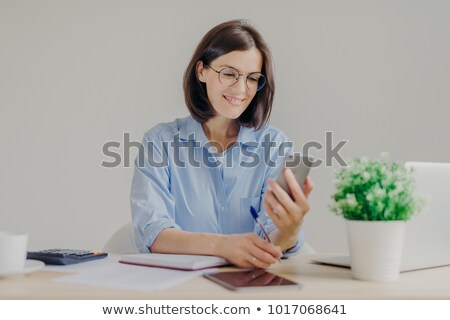 Stockfoto: Pretty Successful Talented Female Copywriter Blogs On Smart Phone Works On Laptop Computer Checks