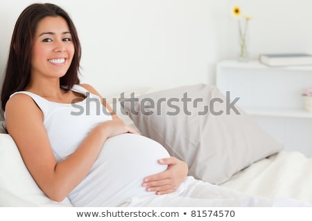 Stockfoto: Cute Pregnant Woman Touching Her Belly While Lying On A Bed At Home