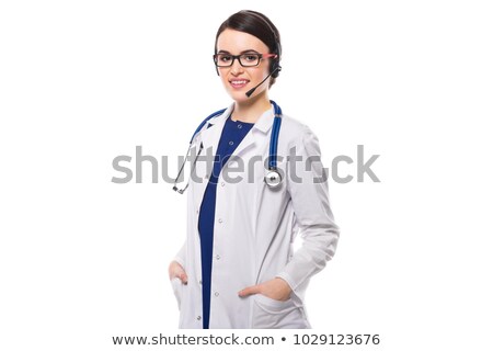 Foto stock: Young Woman Doctor With Stethoscope And Headphones Holding Her Hands In Pockets In White Uniform On