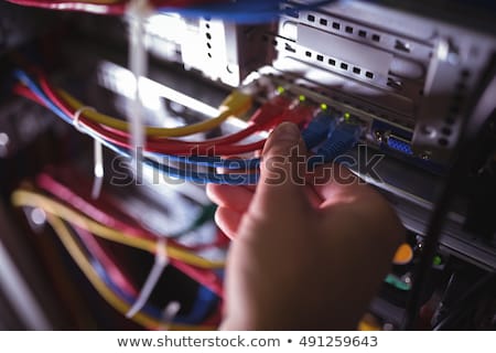 Stock photo: Technician Plugging Patch Cable In A Rack Mounted Server