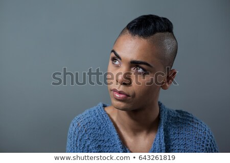 Foto d'archivio: Transgender With Half Shaved Hairstyle Against Gray Background