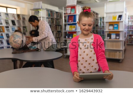 Сток-фото: Front View Of Schoolgirl Studying On Digital Tablet At Table In School Library