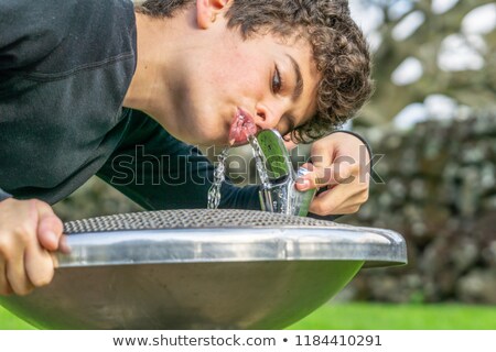 Zdjęcia stock: Boy Is Drinking Water On A Public Fountain