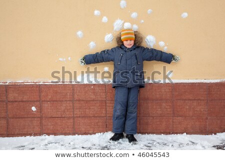 Foto stock: Boy Kid Is Standing Near Wall With Snowballs Snow Stains Risky Bombardment Shooting Of Defenceless