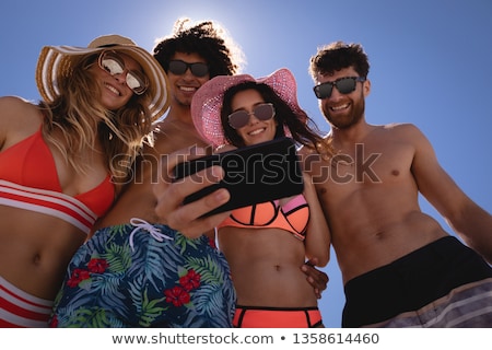 ストックフォト: Low Angle View Of Happy Young Friends Taking Selfie Against Clear Sky