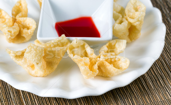 Crispy fried wanton and sauce in white bowl on bamboo mat Stock photo © tab62