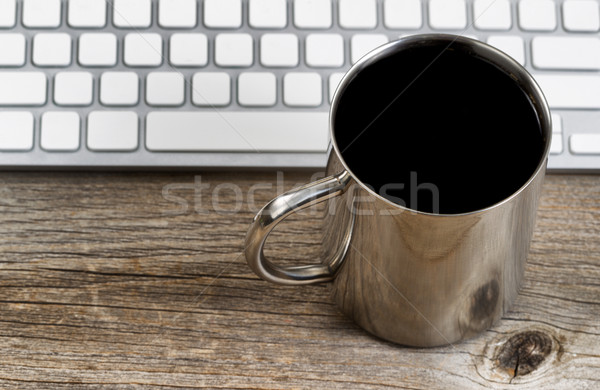 Fresh dark cup of coffee with keyboard on rustic wooden desktop Stock photo © tab62