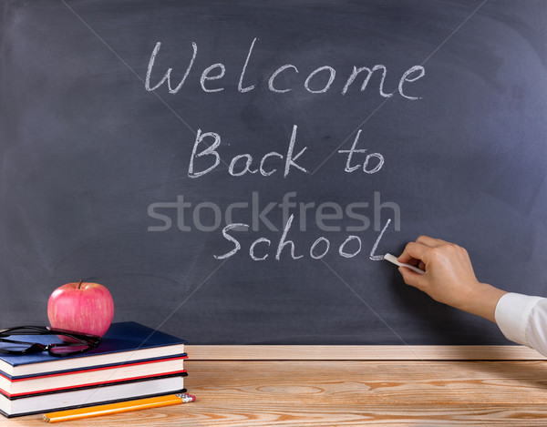 Teacher writing welcome back to school on erased black chalkboar Stock photo © tab62