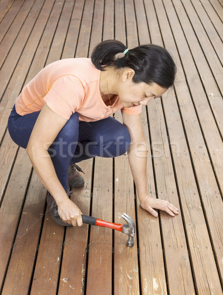 Stock photo: Mature woman working on Deck with Hammer 