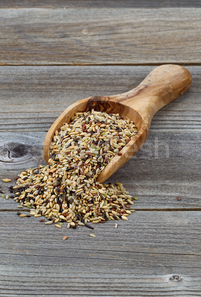 Raw rice in wooden scoop spilling onto rustic wood Stock photo © tab62