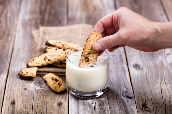 Hand dipping homemade chocolate chip cookies into full glass of  Stock photo © tab62