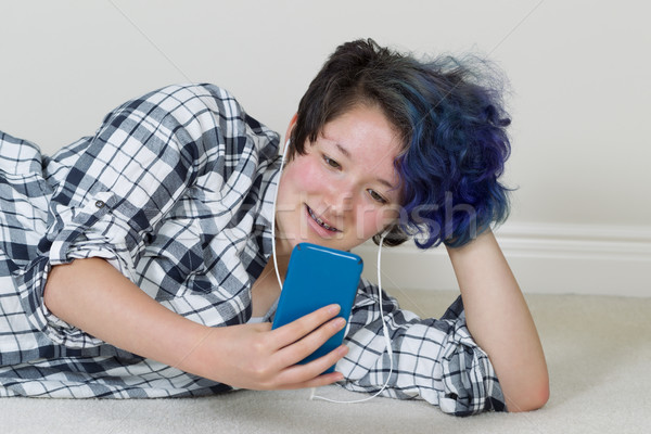 Teenage girl using her cell phone and listening to music at home Stock photo © tab62