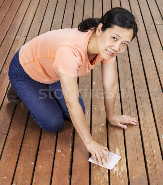 Matue woman sanding natural cedar wooden deck by hand Stock photo © tab62