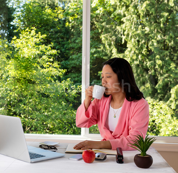 Stock photo: Mature woman enjoying her coffee in the morning while working fr