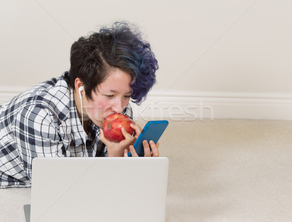 Teenage girl eating apple while using her cell phone and listeni Stock photo © tab62