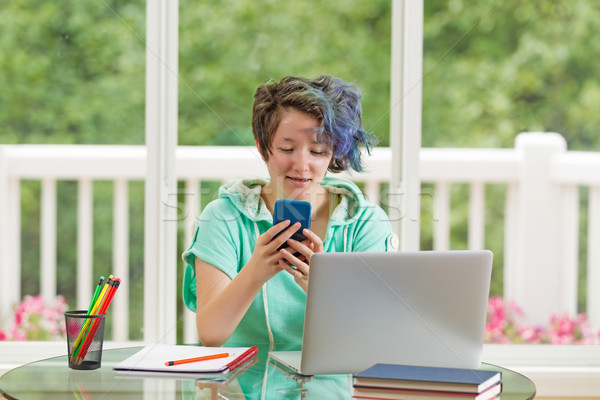 Teenage girl texting while working on her studies at home   Stock photo © tab62