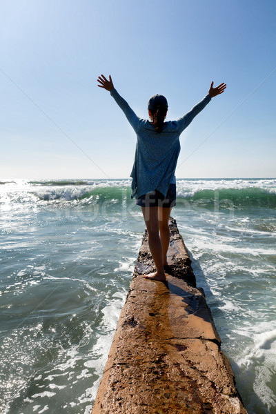 Woman walking out onto break wall with waves of ocean in front   Stock photo © tab62